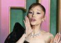 Fotografía de Ariana Grande con un vestigo negro de gala diciendo algo y poniendo su mano sobre su rostro