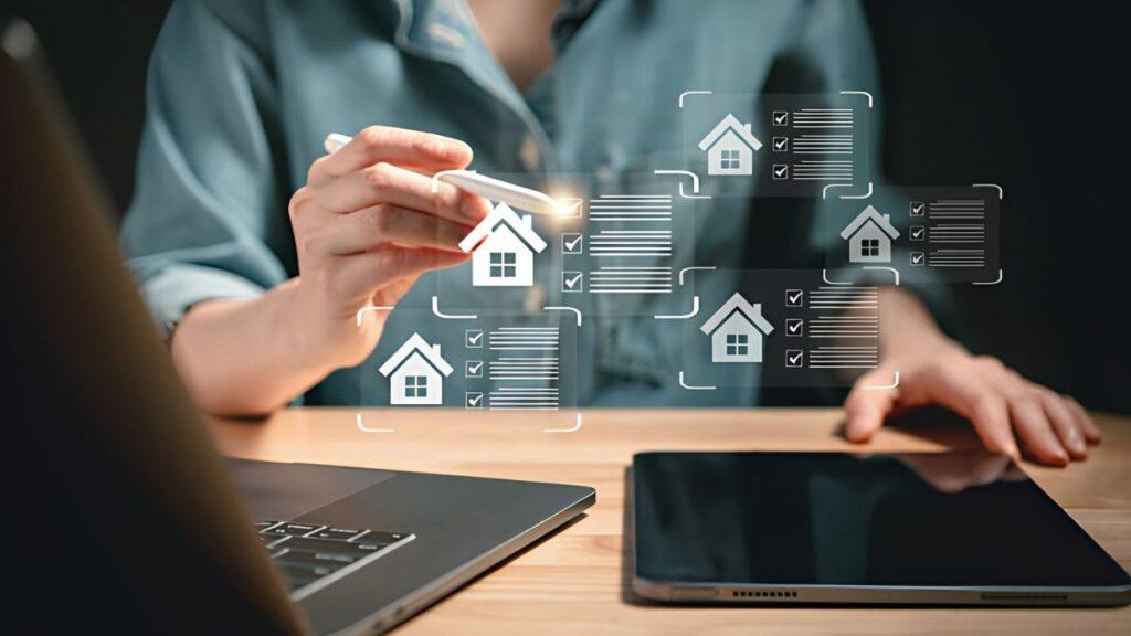 comprar-una-casa-propiedad-quantium - CLAVE NOTICIA Person using a stylus to interact with holographic real estate documents and house icons on a desk, suggesting digital property management.